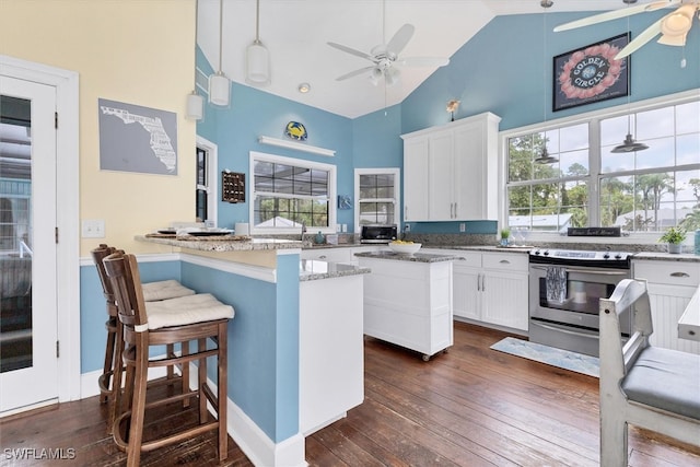 kitchen featuring dark hardwood / wood-style floors, pendant lighting, high vaulted ceiling, white cabinets, and stainless steel range