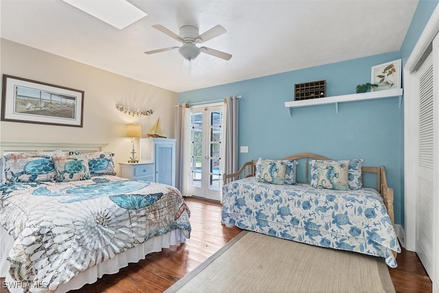 bedroom featuring ceiling fan, access to outside, dark hardwood / wood-style flooring, a skylight, and a closet