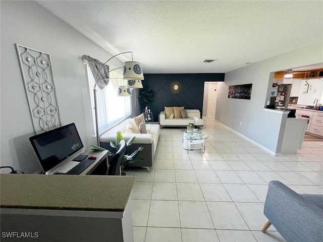 tiled living room with a textured ceiling and sink