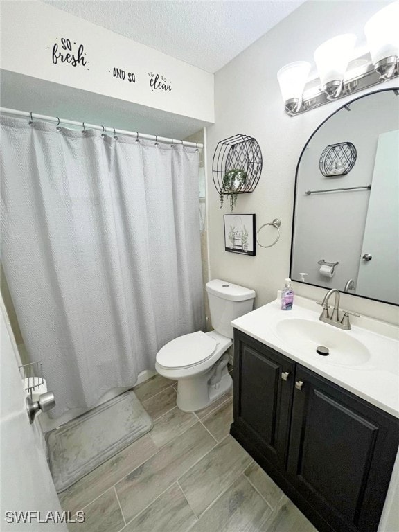 bathroom with a textured ceiling, toilet, hardwood / wood-style flooring, vanity, and curtained shower