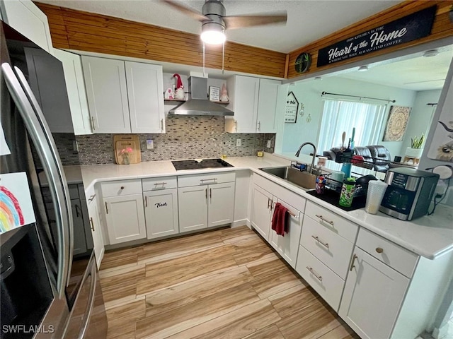 kitchen featuring wall chimney exhaust hood, white cabinets, stainless steel fridge, and sink