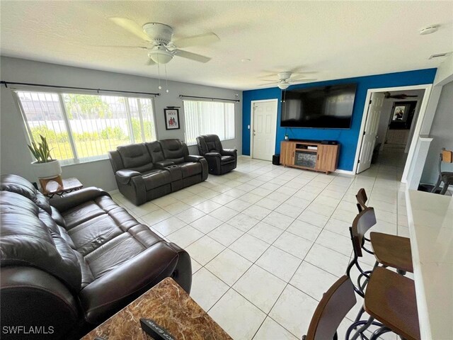 tiled living room with a textured ceiling, a healthy amount of sunlight, and ceiling fan