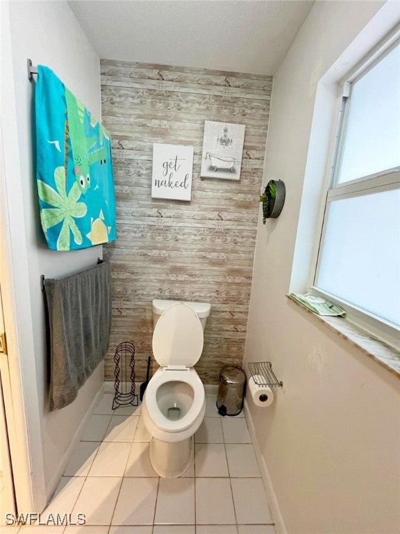 bathroom featuring wooden walls, tile patterned flooring, and toilet