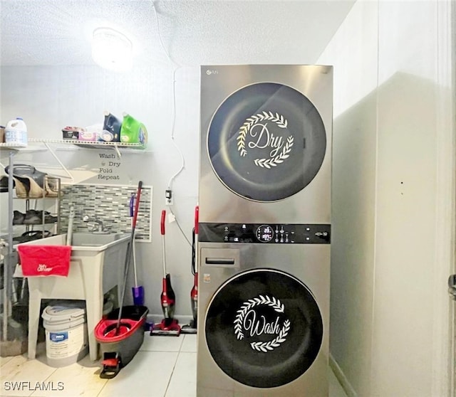 clothes washing area featuring stacked washer and dryer, a textured ceiling, and light tile patterned flooring