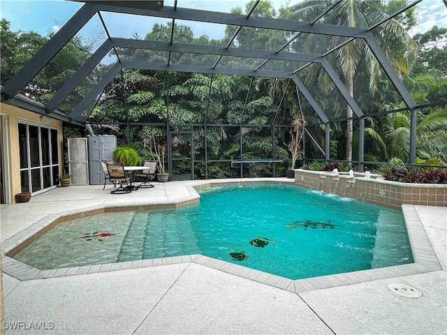 view of pool with pool water feature, a patio, and glass enclosure