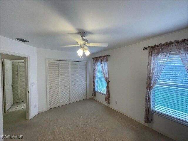 unfurnished bedroom with ceiling fan, light colored carpet, and a closet