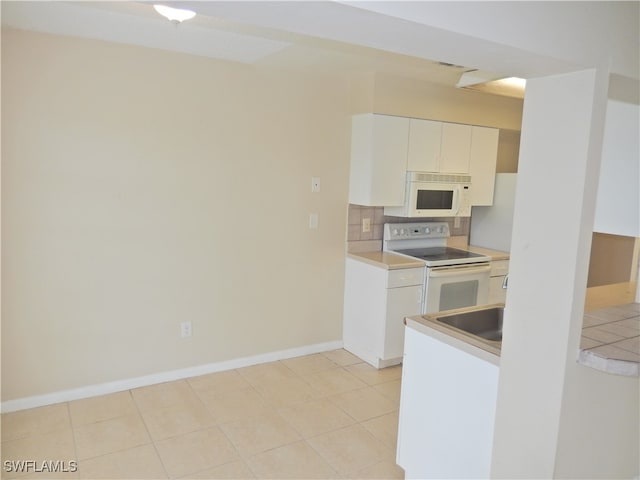 kitchen featuring white appliances, white cabinetry, backsplash, and light tile patterned floors