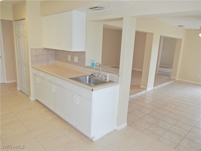 kitchen with white cabinets, light tile patterned flooring, decorative backsplash, and sink