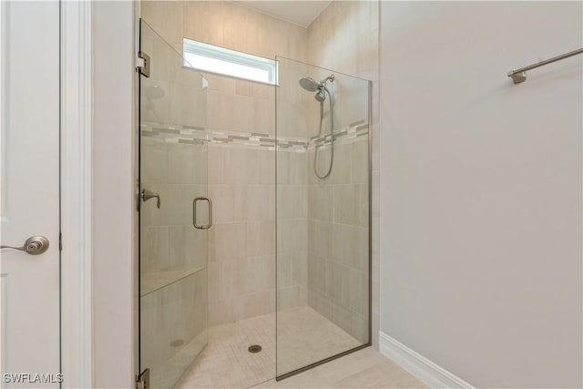 bathroom featuring tiled shower and baseboards