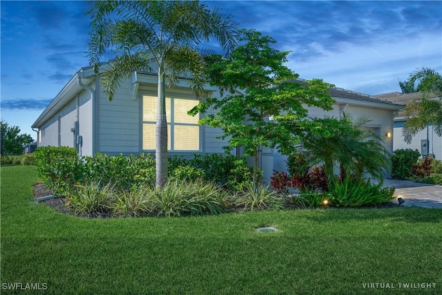 view of side of property with a yard, decorative driveway, and an attached garage