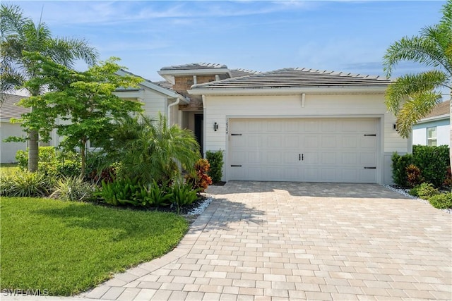 view of front of house with decorative driveway, an attached garage, and a tile roof