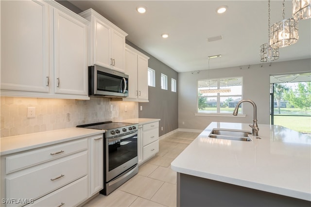 kitchen featuring tasteful backsplash, light tile patterned floors, stainless steel appliances, an island with sink, and sink