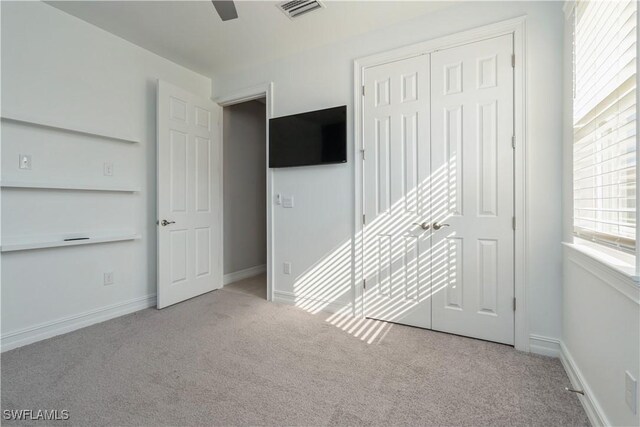 unfurnished bedroom with light colored carpet, ceiling fan, and a closet