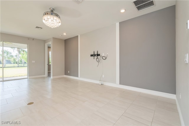 tiled empty room with an inviting chandelier