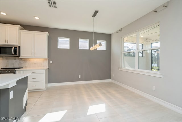 kitchen with light tile patterned floors, backsplash, stainless steel appliances, and pendant lighting