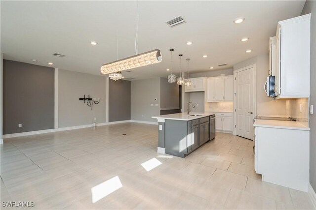 kitchen with light tile patterned floors, tasteful backsplash, a center island with sink, and sink