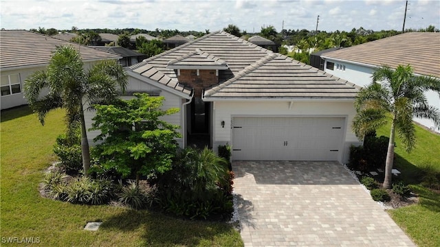 view of front of house with a front yard, decorative driveway, a tile roof, and an attached garage