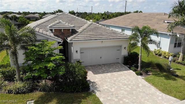 view of front of house with a garage, a tile roof, decorative driveway, and a front yard