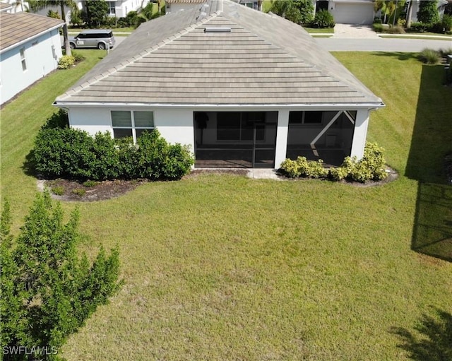 rear view of property with a lawn, a sunroom, and stucco siding