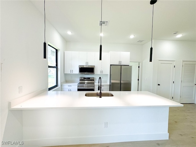 kitchen featuring light wood-type flooring, stainless steel appliances, hanging light fixtures, and sink