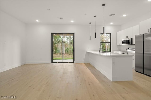 kitchen with pendant lighting, a healthy amount of sunlight, appliances with stainless steel finishes, and white cabinets