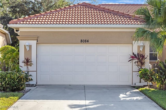 8084 Sanctuary Dr Unit 1, Naples, FL 34104 - view of front of property featuring stucco siding, concrete driveway, a tiled roof, and a garage