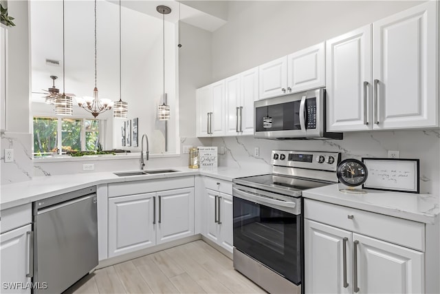 kitchen with sink, decorative light fixtures, white cabinetry, stainless steel appliances, and an inviting chandelier