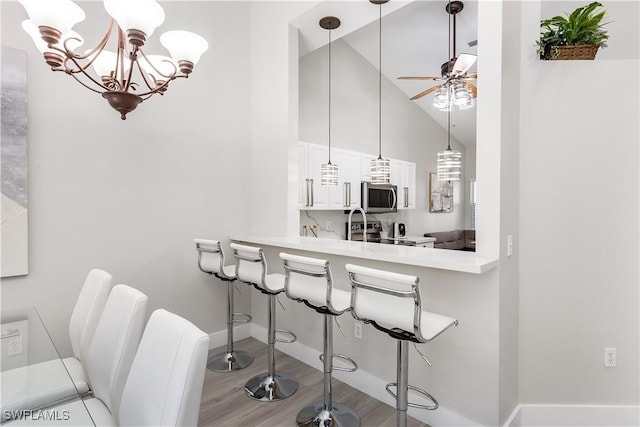 8084 Sanctuary Dr Unit 1, Naples, FL 34104 - kitchen with stainless steel appliances, a breakfast bar area, light countertops, a chandelier, and ceiling fan