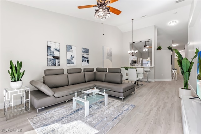 living room featuring ceiling fan with notable chandelier, light hardwood / wood-style floors, and high vaulted ceiling