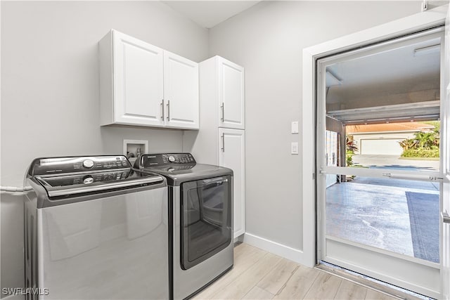 washroom featuring cabinets, light hardwood / wood-style floors, and washing machine and dryer