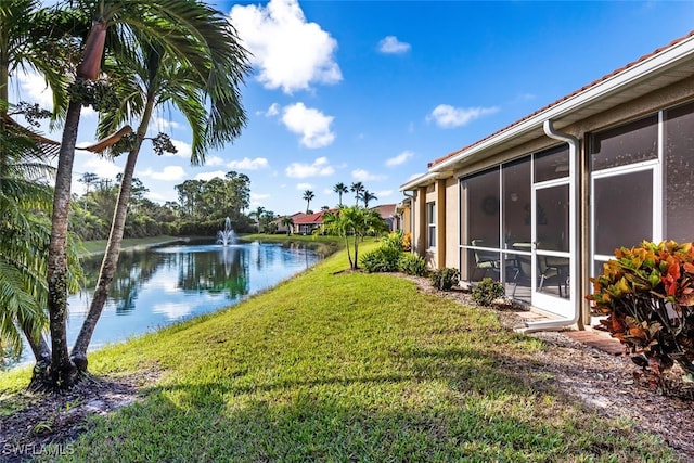 view of yard featuring a sunroom and a water view