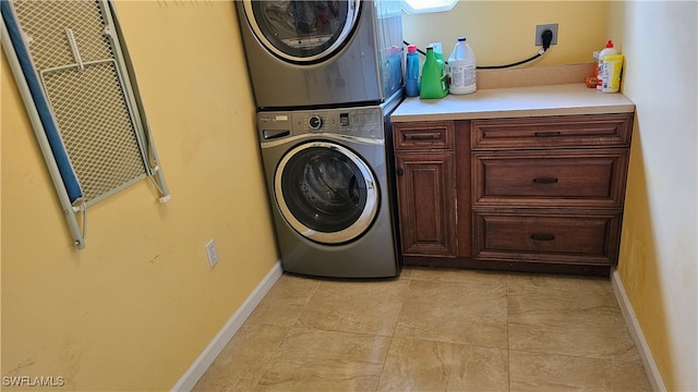 washroom featuring stacked washer / dryer, light tile patterned flooring, and cabinets