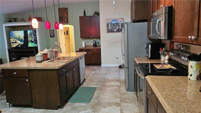 kitchen featuring a kitchen island with sink, sink, decorative light fixtures, light stone counters, and stainless steel appliances