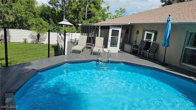 view of swimming pool with a wooden deck, a sunroom, and a yard