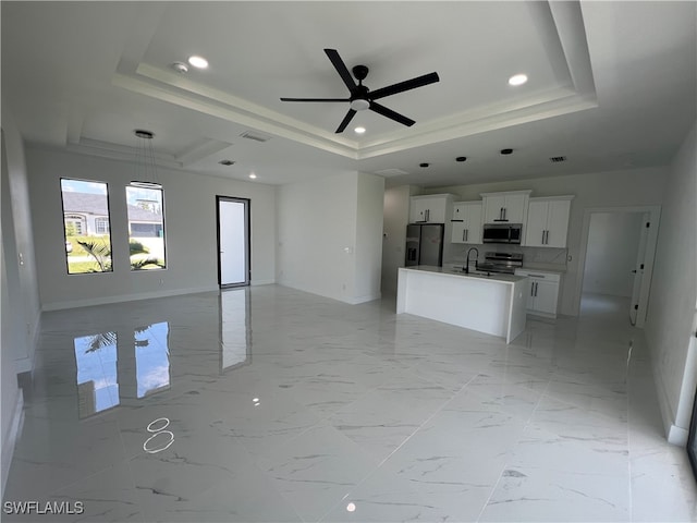 unfurnished living room featuring sink, ceiling fan, a raised ceiling, and light tile patterned floors