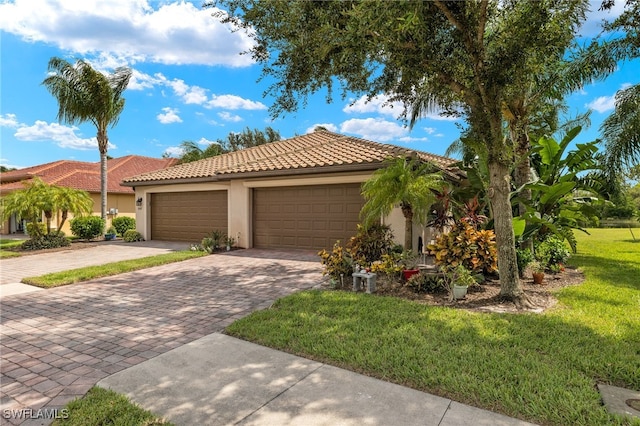 view of front of house featuring a tiled roof, an attached garage, decorative driveway, a front lawn, and stucco siding