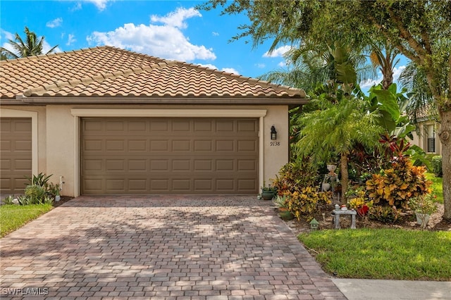 view of front of property with a garage, driveway, a tiled roof, and stucco siding