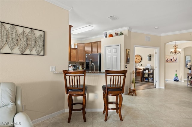 kitchen featuring arched walkways, stainless steel fridge, visible vents, and a kitchen bar