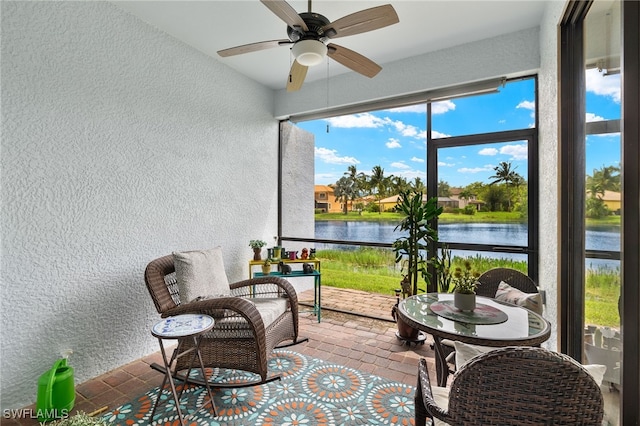 sunroom with a water view and ceiling fan