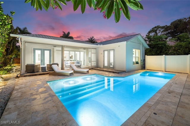 pool at dusk featuring a patio area and french doors