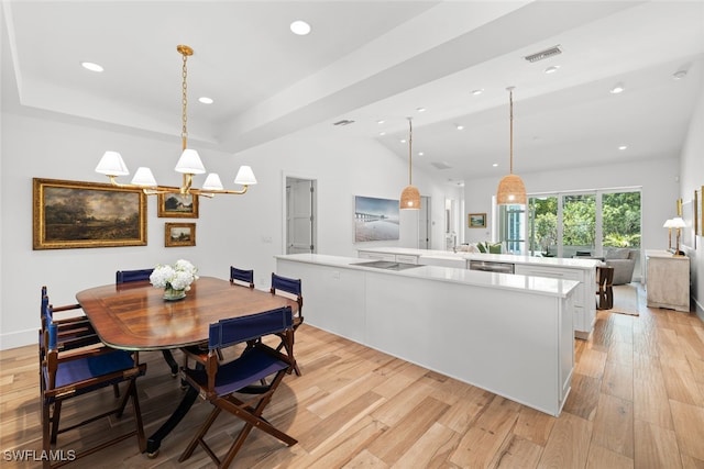 dining space featuring a raised ceiling, light hardwood / wood-style floors, and vaulted ceiling