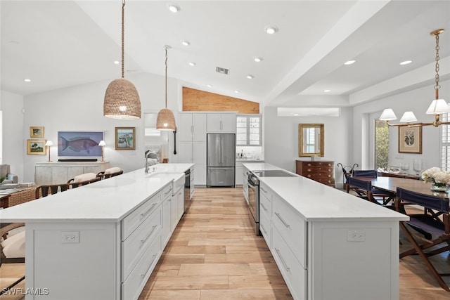 kitchen with a wealth of natural light, a large island, hanging light fixtures, and appliances with stainless steel finishes