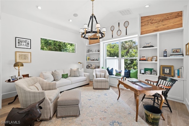 living room with a notable chandelier, a healthy amount of sunlight, lofted ceiling, and light hardwood / wood-style floors