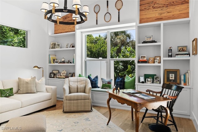 sitting room featuring built in shelves, light hardwood / wood-style flooring, and a notable chandelier