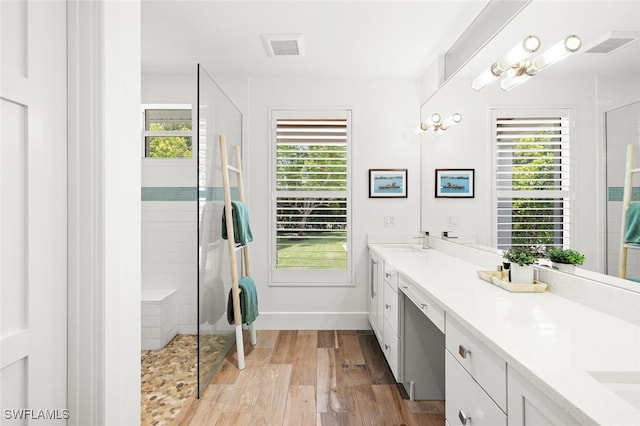 bathroom featuring wood-type flooring, vanity, a tile shower, and plenty of natural light