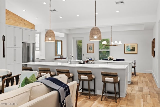 kitchen featuring sink, hanging light fixtures, high end fridge, a breakfast bar, and white cabinets