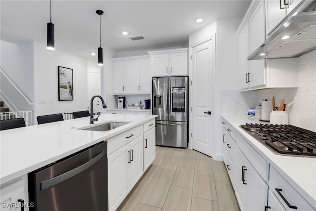 kitchen with sink, ventilation hood, pendant lighting, stainless steel appliances, and white cabinets