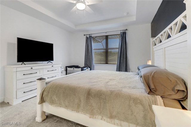 bedroom featuring light colored carpet, a raised ceiling, and ceiling fan