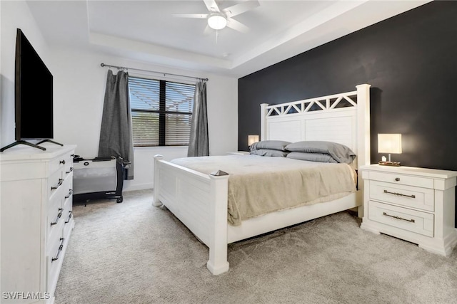 carpeted bedroom featuring ceiling fan and a tray ceiling