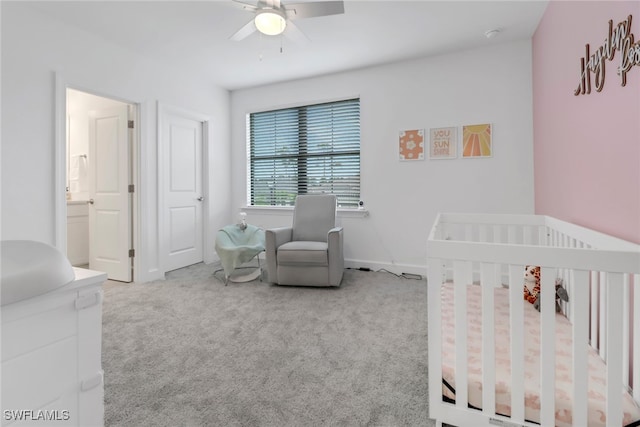 bedroom featuring a crib, light colored carpet, and ceiling fan